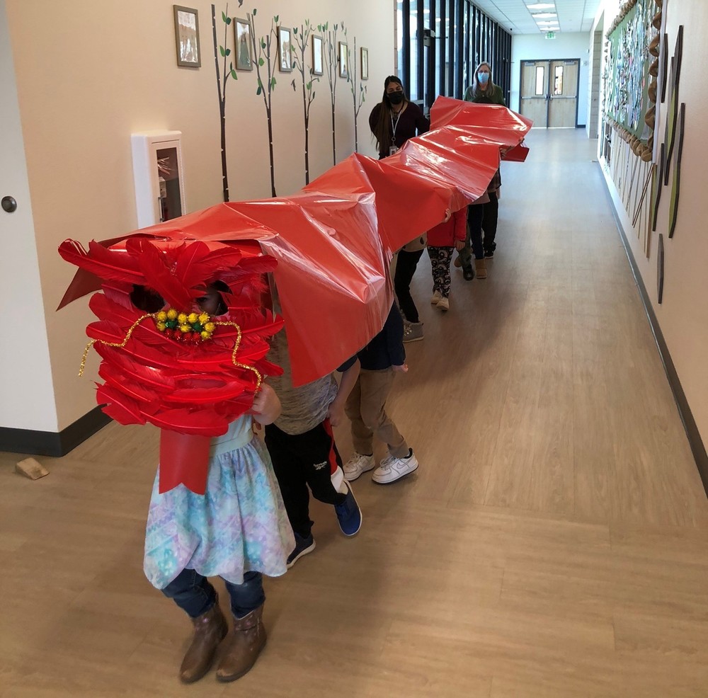 Students from Shining Stars Preschool dragon dance down the hallway in celebration of Chinese New Year