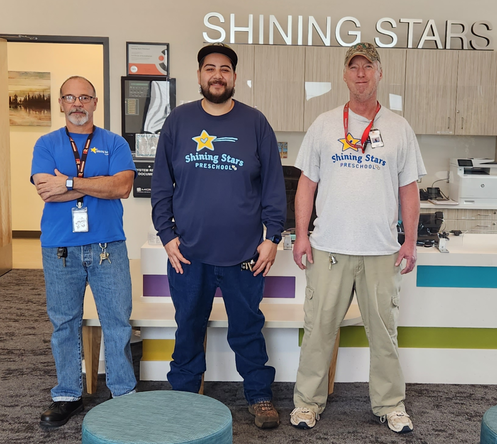 3 people stand in front of a desk