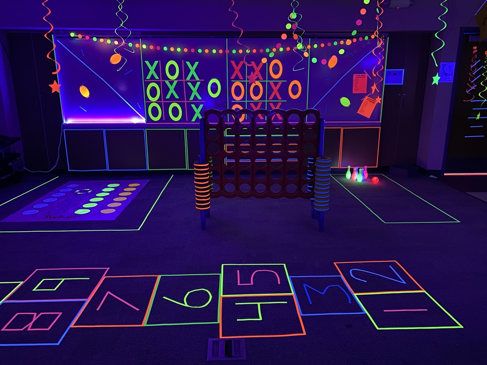 Photo of the glow room at Maggie Cordova Elementary with a glow in the dark hop scotch and tick tack toe board